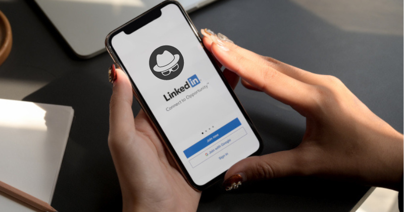 A person holding a phone with the linkedin app on it.