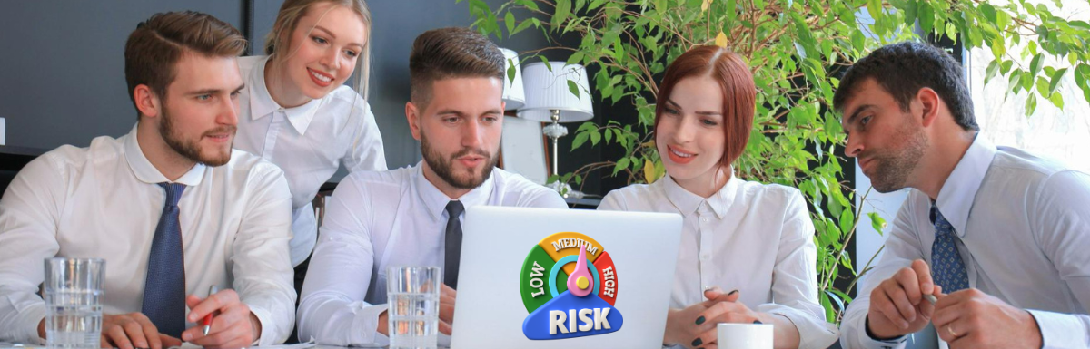 A group of people looking at a laptop with the word risk on it.