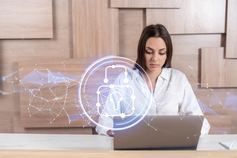 A woman is sitting at a desk with a laptop in front of her.