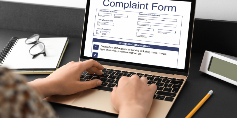 A person using a complaint management system to enter a complaint on a laptop.