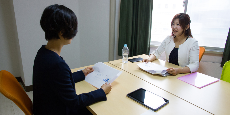 Two women sitting at a table talking to each other.