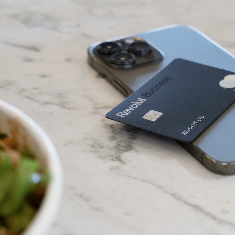 A phone featuring a credit card near a bowl of salad, symbolizing the convenience of mobile payments for business transactions.