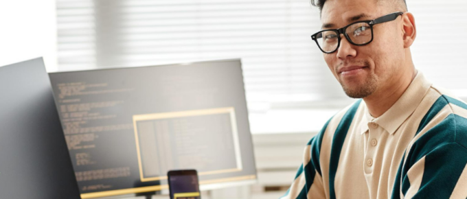A man in glasses sitting in front of a computer.