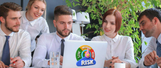 A group of people looking at a laptop with the word risk on it.