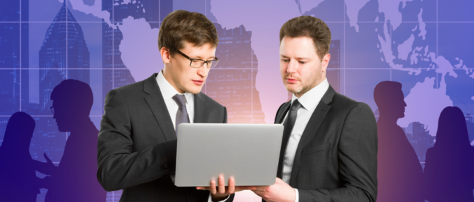 Two businessmen looking at a laptop in front of a city.