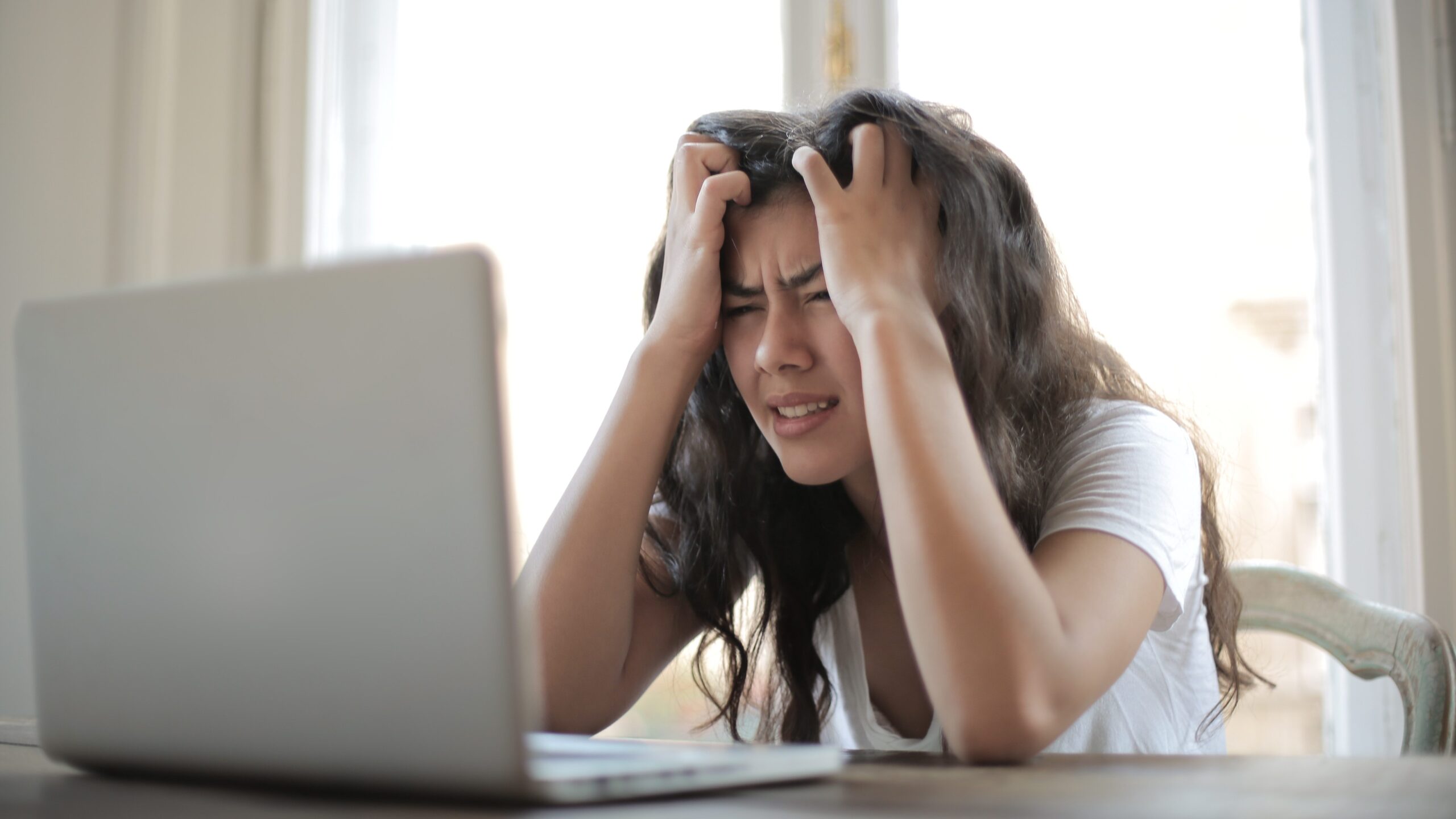 Eine Frau hält ihren Kopf vor ihren Laptop.