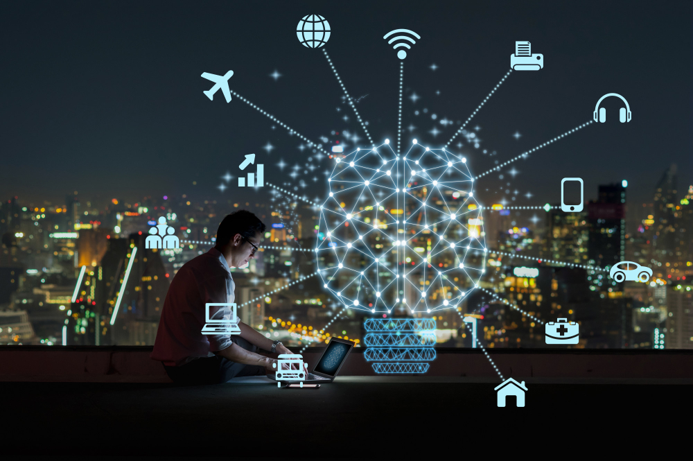 A man working on a laptop at night with a city in the background.