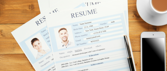 A resume placed alongside a cup of coffee on a wooden table.
