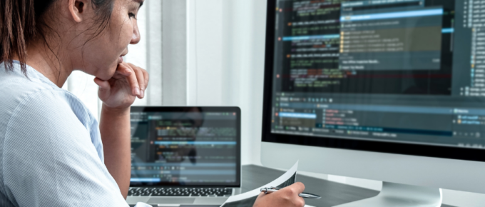 A woman is programming in JavaScript using an asynchronous method on her computer screen.