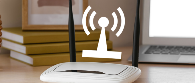 A wireless router on a desk next to a laptop.
