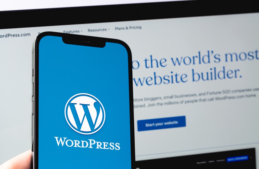 WordPress logo mobile app on screen smartphone iPhone with Macbook display closeup. WordPress - open source site content management system. Moscow, Russia - June 22, 2021
